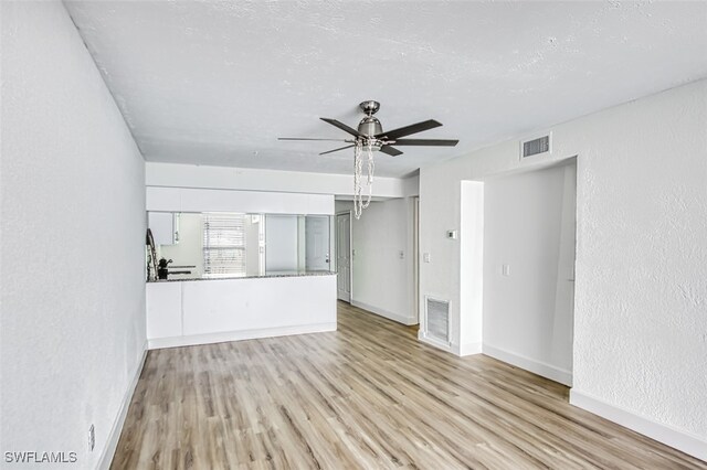 unfurnished living room featuring ceiling fan, visible vents, and wood finished floors