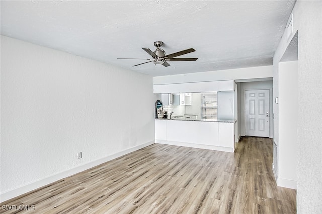 unfurnished living room featuring light hardwood / wood-style floors, a textured ceiling, and ceiling fan