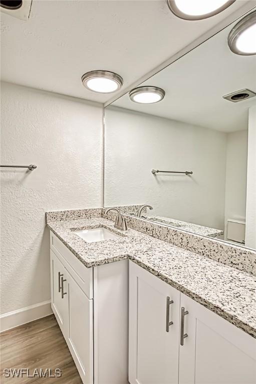 16251 Dublin Cir Unit F104, Fort Myers, FL 33908 - bathroom featuring visible vents, wood finished floors, baseboards, vanity, and a textured wall