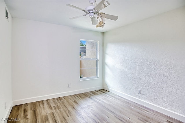 spare room featuring a ceiling fan, baseboards, visible vents, and wood finished floors