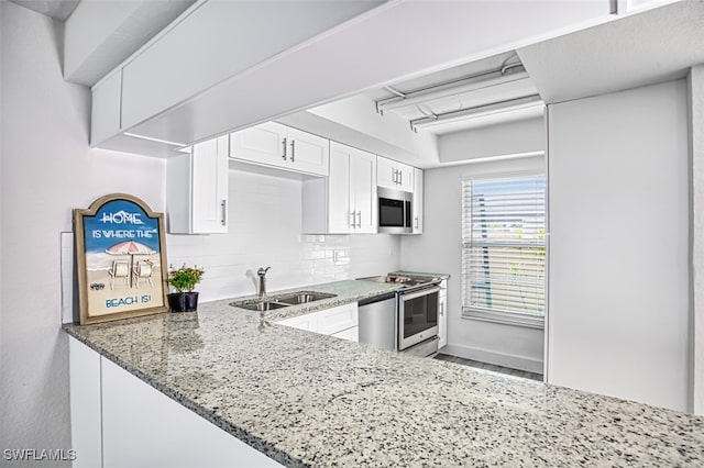 kitchen featuring light stone countertops, appliances with stainless steel finishes, sink, white cabinetry, and decorative backsplash