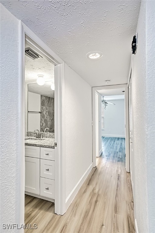 corridor with light hardwood / wood-style floors and a textured ceiling