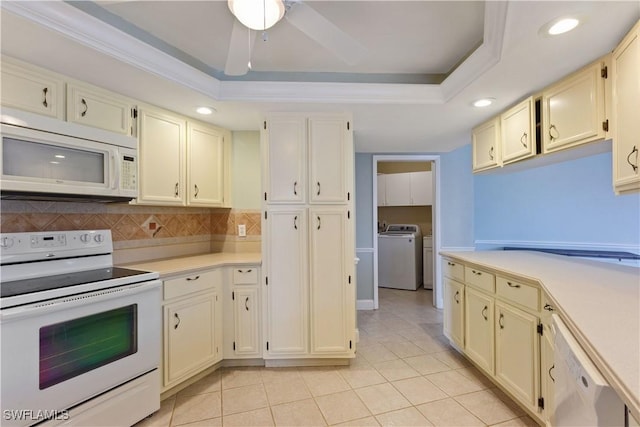 kitchen with decorative backsplash, white appliances, a tray ceiling, and washing machine and dryer