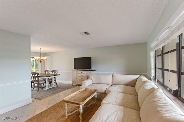 living room with a notable chandelier, light tile patterned flooring, and a textured ceiling