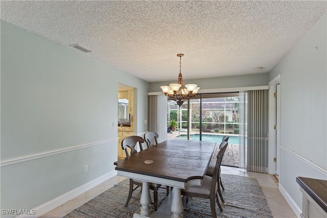 dining space featuring light tile patterned flooring, a textured ceiling, and a notable chandelier