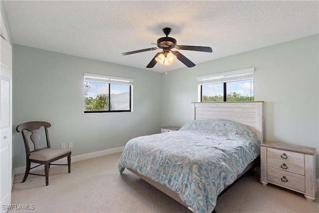 bedroom with ceiling fan, light carpet, and a textured ceiling