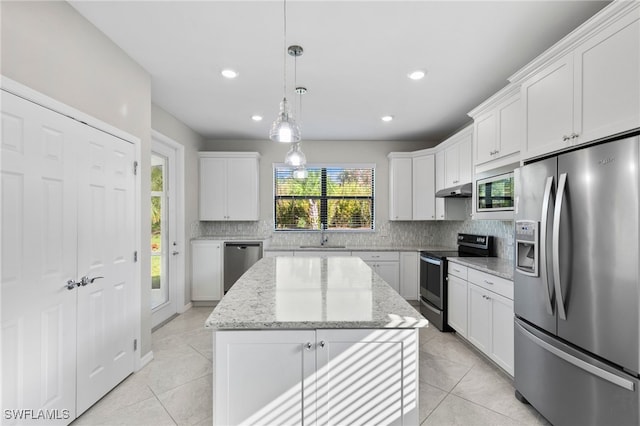 kitchen with tasteful backsplash, white cabinetry, light stone countertops, stainless steel appliances, and a center island