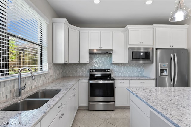 kitchen with tasteful backsplash, appliances with stainless steel finishes, sink, hanging light fixtures, and white cabinetry