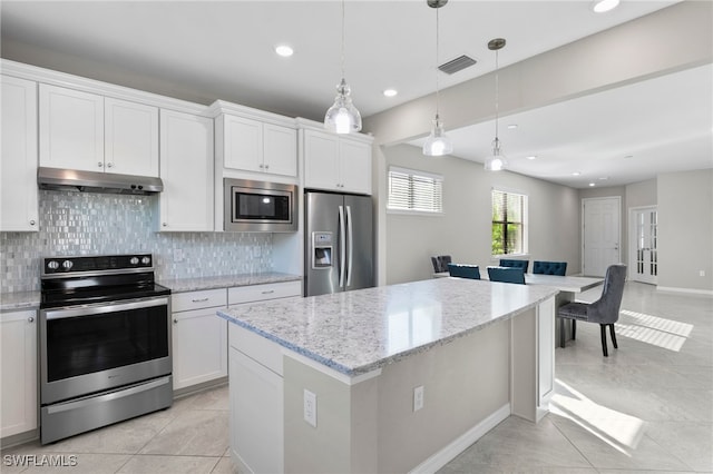 kitchen with decorative backsplash, appliances with stainless steel finishes, hanging light fixtures, and white cabinets