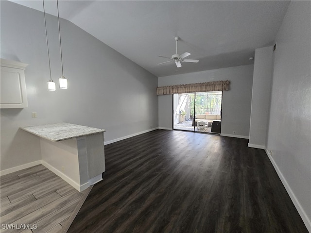 unfurnished living room featuring dark hardwood / wood-style flooring, vaulted ceiling, and ceiling fan