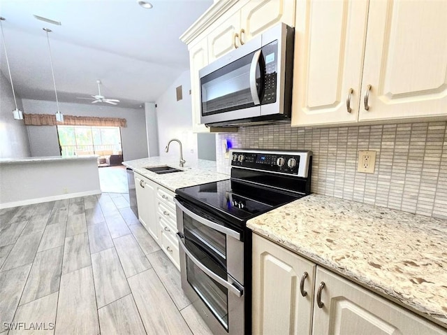 kitchen with vaulted ceiling, appliances with stainless steel finishes, sink, light stone counters, and ceiling fan