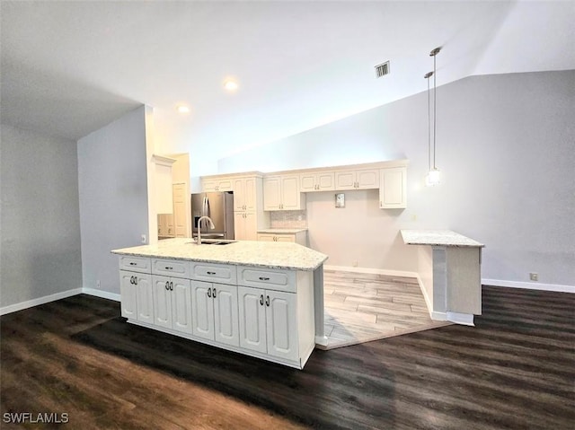 kitchen with lofted ceiling, light stone counters, dark hardwood / wood-style floors, pendant lighting, and white cabinets