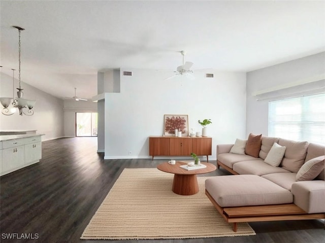 living room featuring dark wood-type flooring, lofted ceiling, and ceiling fan with notable chandelier