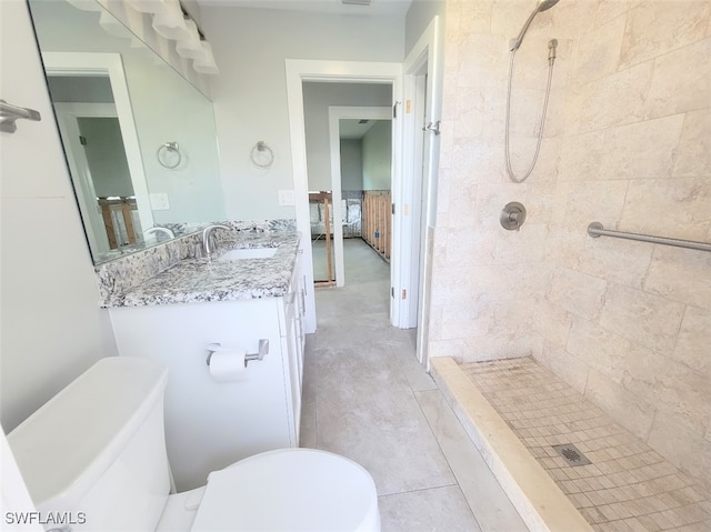 bathroom with toilet, vanity, and a tile shower