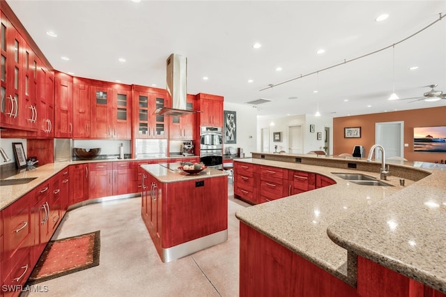 kitchen with a spacious island, wall chimney range hood, sink, and hanging light fixtures