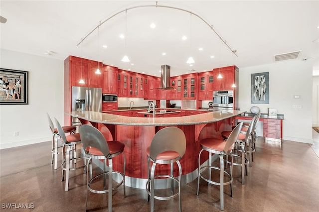 kitchen featuring exhaust hood, a kitchen island with sink, stone countertops, pendant lighting, and stainless steel appliances