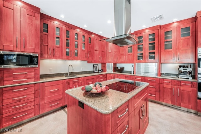 kitchen with island exhaust hood, light stone counters, stainless steel appliances, sink, and a center island