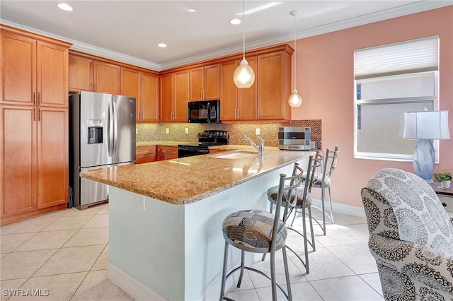 kitchen with kitchen peninsula, light stone counters, black appliances, pendant lighting, and sink