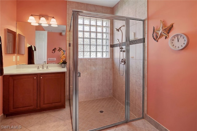 bathroom with a shower with door, vanity, and tile patterned flooring