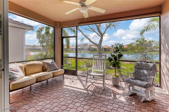 sunroom / solarium featuring a water view and ceiling fan