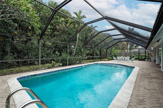 view of pool with glass enclosure and a patio