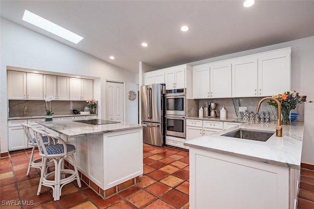 kitchen with a center island, sink, vaulted ceiling with skylight, decorative backsplash, and stainless steel appliances