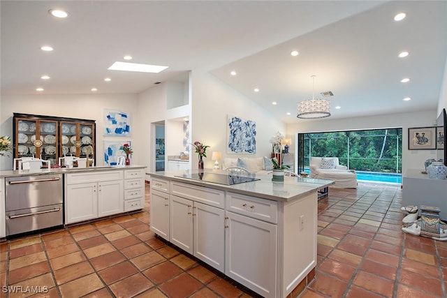 kitchen featuring black electric stovetop, lofted ceiling with skylight, pendant lighting, a center island, and white cabinetry