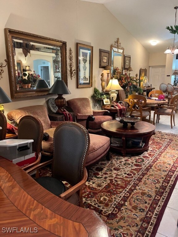 living room featuring light tile patterned floors, a notable chandelier, and vaulted ceiling