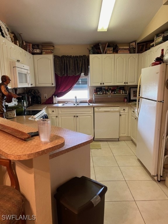 kitchen featuring light tile patterned flooring, sink, a kitchen bar, kitchen peninsula, and white appliances