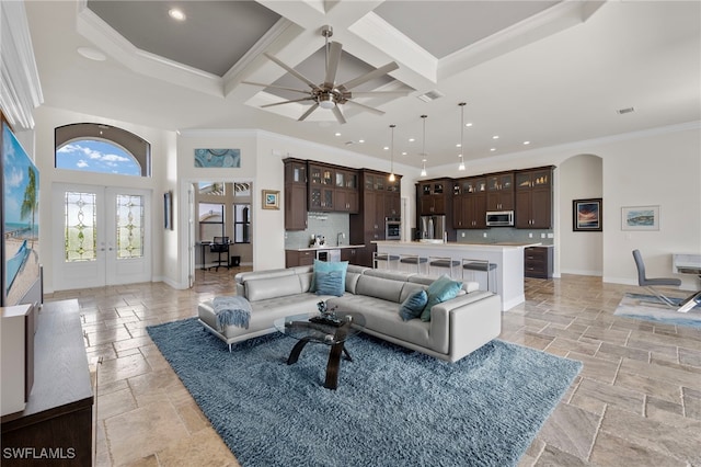 living room featuring french doors, coffered ceiling, a high ceiling, beam ceiling, and ornamental molding