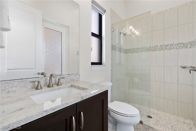 bathroom featuring toilet, vanity, and a tile shower