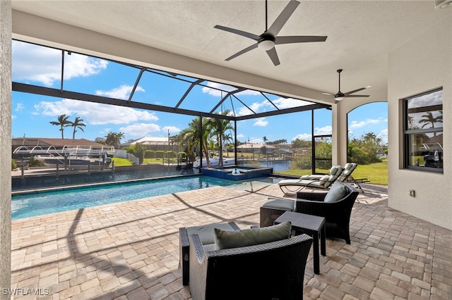 view of pool with an in ground hot tub, glass enclosure, a patio, ceiling fan, and a water view