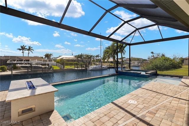 view of pool with an in ground hot tub, a patio, a water view, and glass enclosure