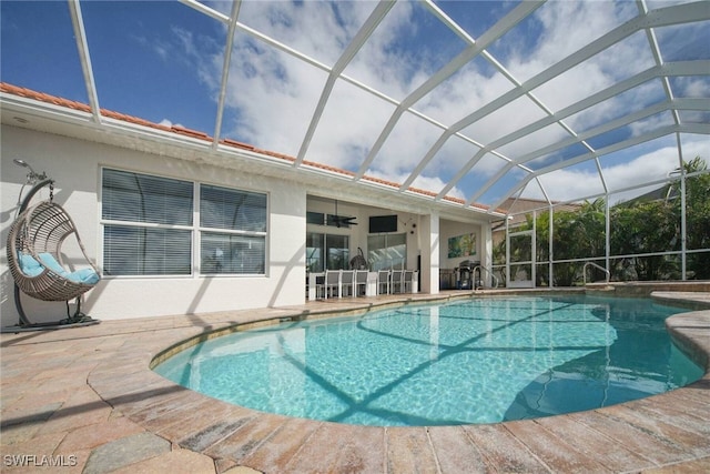 view of pool with ceiling fan, a lanai, and a patio area