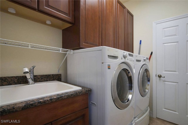 clothes washing area featuring sink, cabinets, and separate washer and dryer