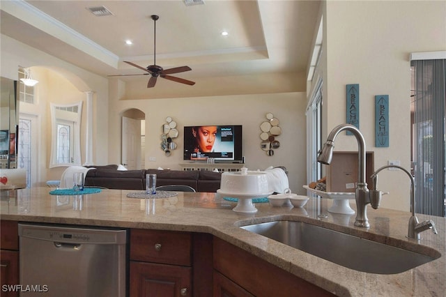 kitchen with sink, a tray ceiling, ceiling fan, stainless steel dishwasher, and light stone counters