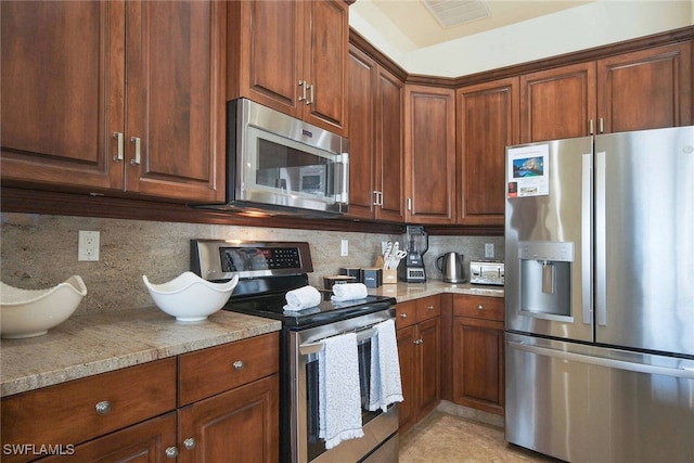 kitchen featuring light stone countertops, tasteful backsplash, and appliances with stainless steel finishes