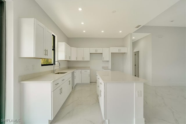 kitchen with sink, a kitchen island, and white cabinetry