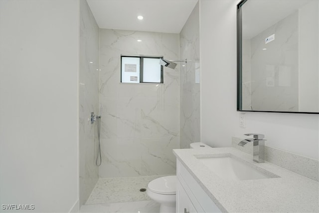 bathroom with vanity, toilet, and tiled shower