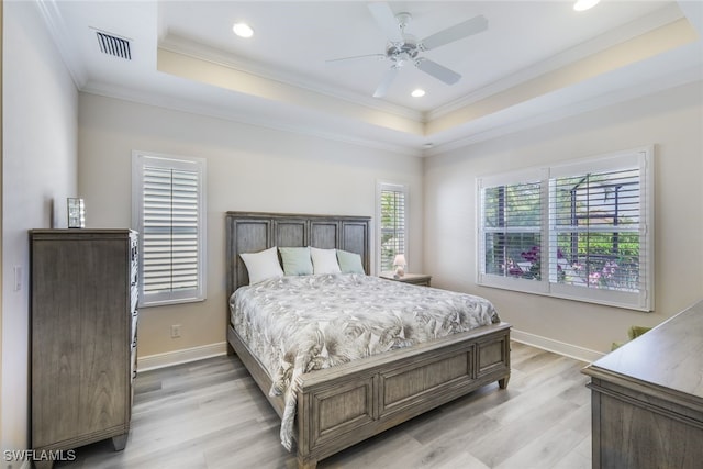 bedroom featuring a tray ceiling, light hardwood / wood-style flooring, ceiling fan, and ornamental molding