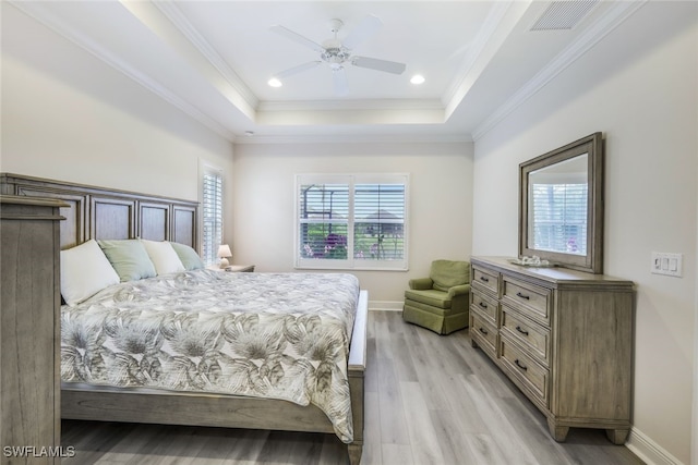 bedroom featuring ceiling fan, a raised ceiling, crown molding, and light hardwood / wood-style flooring