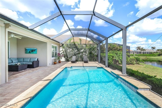 view of pool with glass enclosure, ceiling fan, an outdoor hangout area, a water view, and a patio