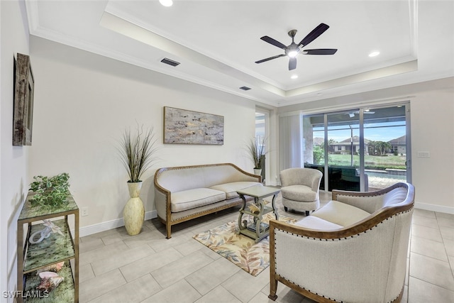 tiled living room with a raised ceiling, ceiling fan, and crown molding