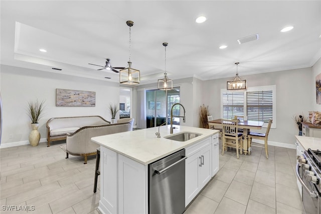 kitchen featuring appliances with stainless steel finishes, a kitchen island with sink, sink, white cabinetry, and hanging light fixtures