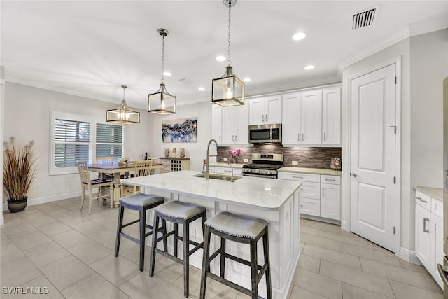 kitchen with appliances with stainless steel finishes, an island with sink, pendant lighting, and sink