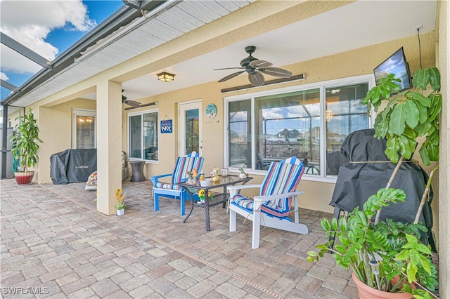 view of patio / terrace featuring ceiling fan and glass enclosure