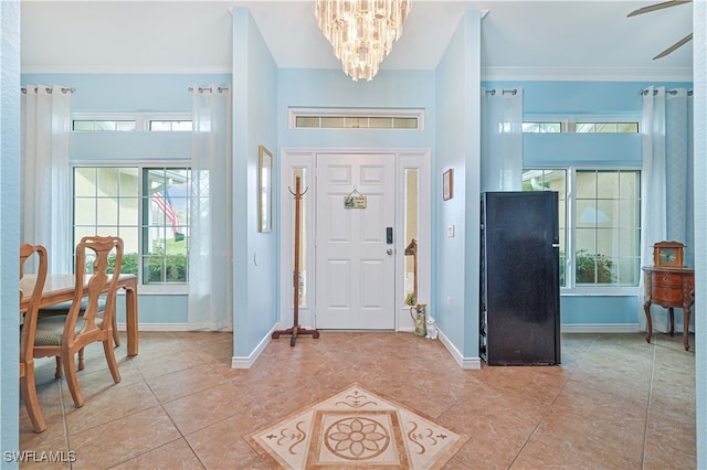 tiled foyer entrance featuring ornamental molding and ceiling fan with notable chandelier