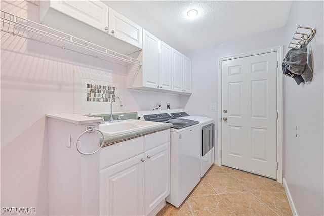 laundry area featuring sink, light tile patterned flooring, independent washer and dryer, a textured ceiling, and cabinets