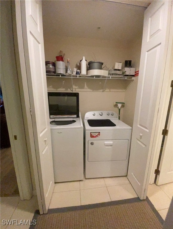 laundry room with washer and clothes dryer and light tile patterned floors