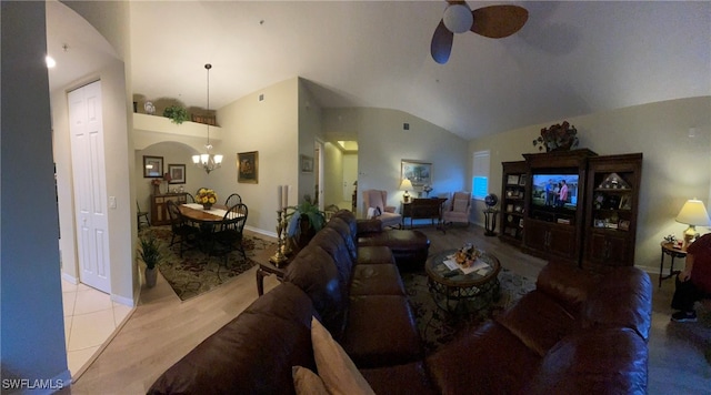 carpeted living room with ceiling fan with notable chandelier and high vaulted ceiling